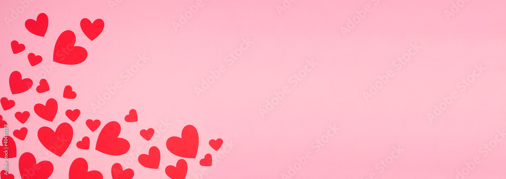Valentines Day corner border of red paper hearts. Overhead view over a pink banner background. Copy space.