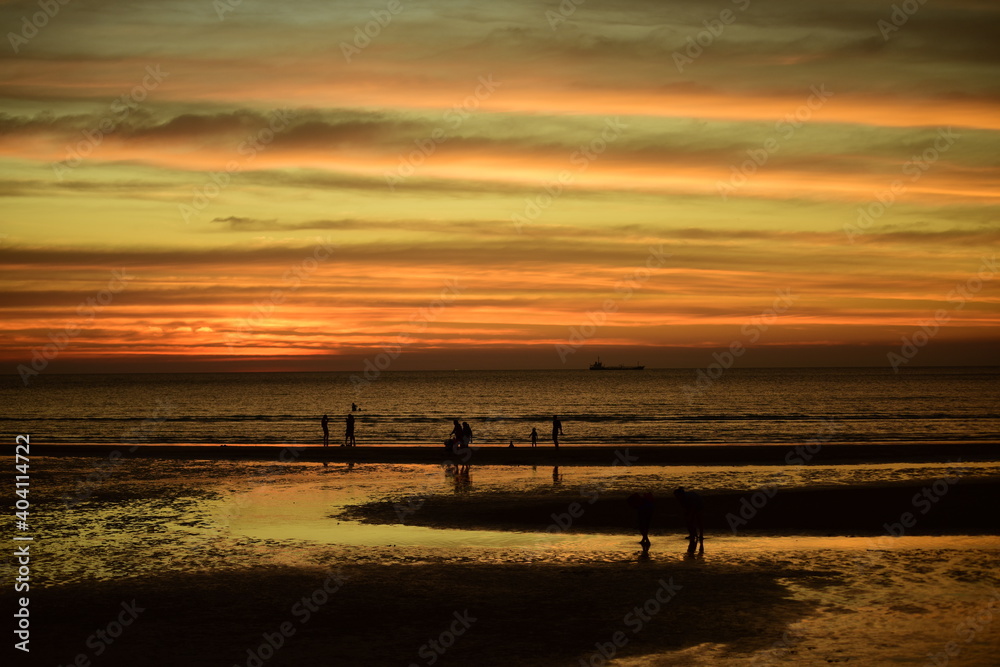 Sunset at the beautiful beach view Among the many people come to play in the sea before the dusk.silhouette of sunset at beach. Sunset at the beautiful beach view Among the many people come to play in the sea before the dusk.silhouette of sunset at beach.