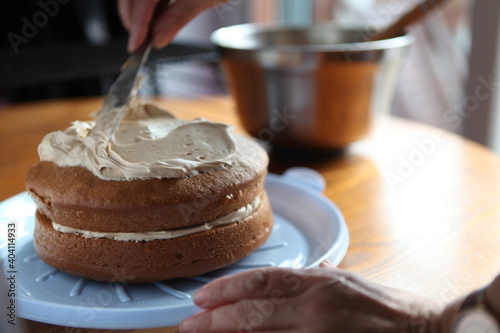 Fotografija Cropped Hand Spreading Cream On Cake
