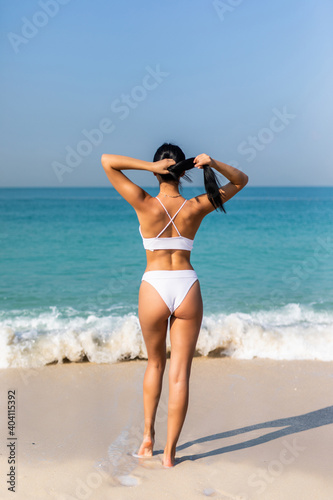 Young woman in white bikini at the sea. Rear View.