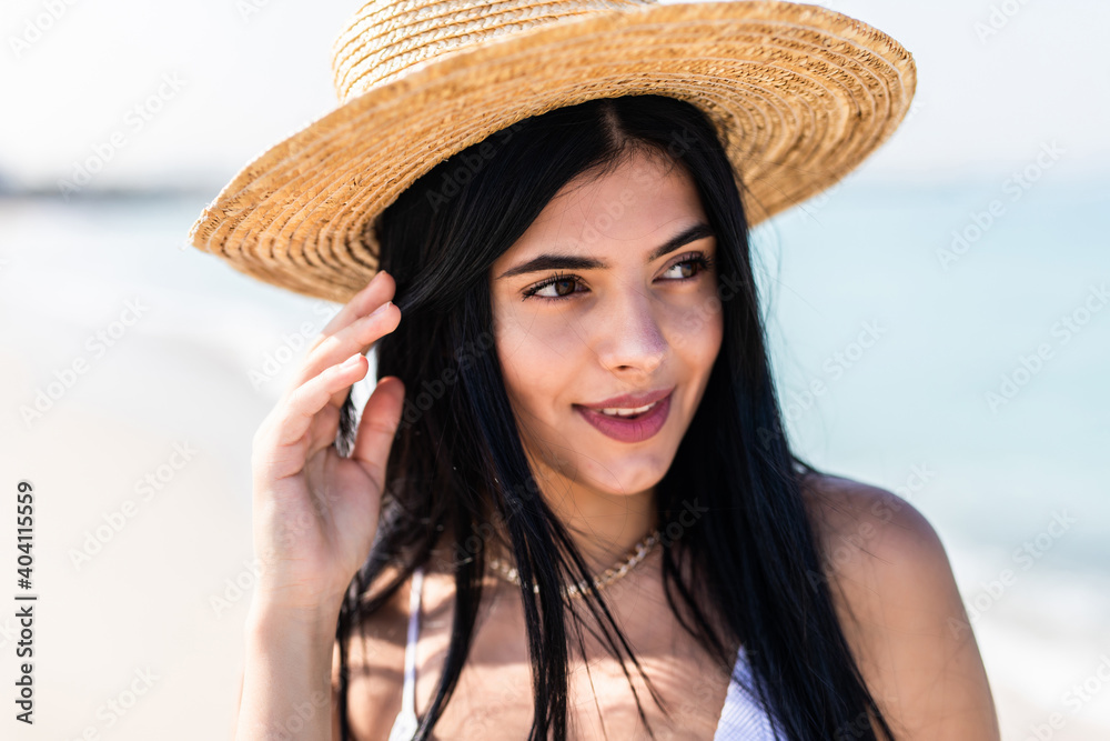 Traveling smiling woman in traw hat spending her leisure time on the beach . Summer mood.