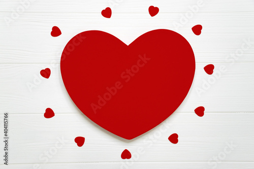 Big red heart and many little hearts on white wooden board as romantic background. Valentine Day, Women`s Day, Mothers Day greeting card or invitation for wedding with copy space.