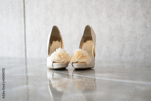 High heel bridal shoes with silk flowers on reflective surface