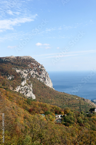 View to the colorful autumn forest on a slope of Crimea mountains with azure black sea on the background