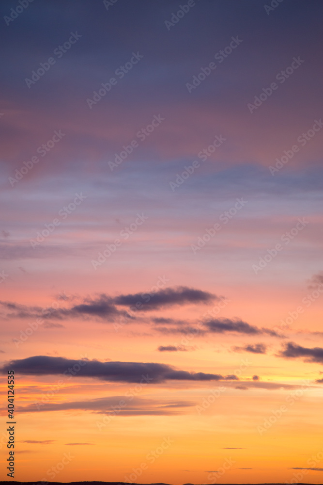 Natural color dramatic dawn or dusk sky with painterly yellow, pink and blue clouds with horizon, taken with telephoto 135 mm lens for sky replacement