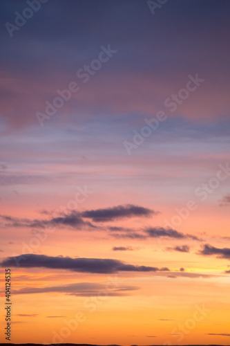 Natural color dramatic dawn or dusk sky with painterly yellow, pink and blue clouds with horizon, taken with telephoto 135 mm lens for sky replacement