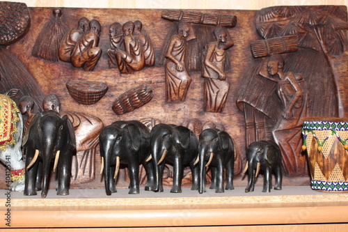 Canvas Print Wooden figures of elephants stand against the background of a wooden panel made