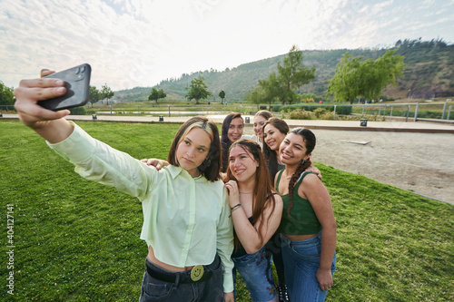 a group of friends trying to take a selfie through their cell phone in a park near the city