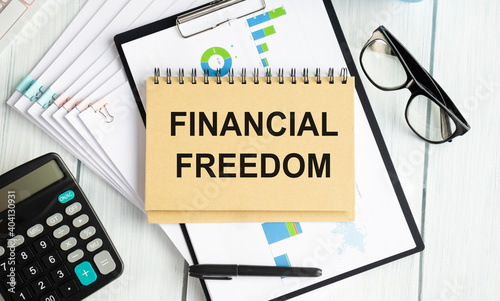 Business concept - Top view notebook writing Financial Freedom