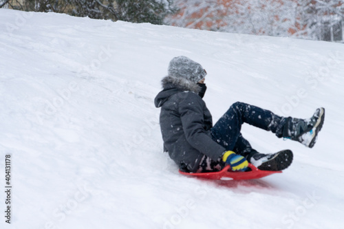 Boy enjoying a sleigh ride. Kid playing outdoors in snow
