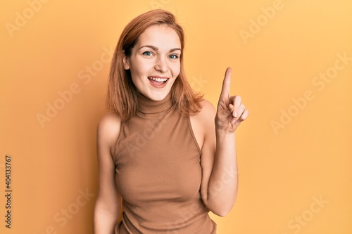 Young caucasian woman wearing casual style with sleeveless dress smiling with an idea or question pointing finger up with happy face, number one