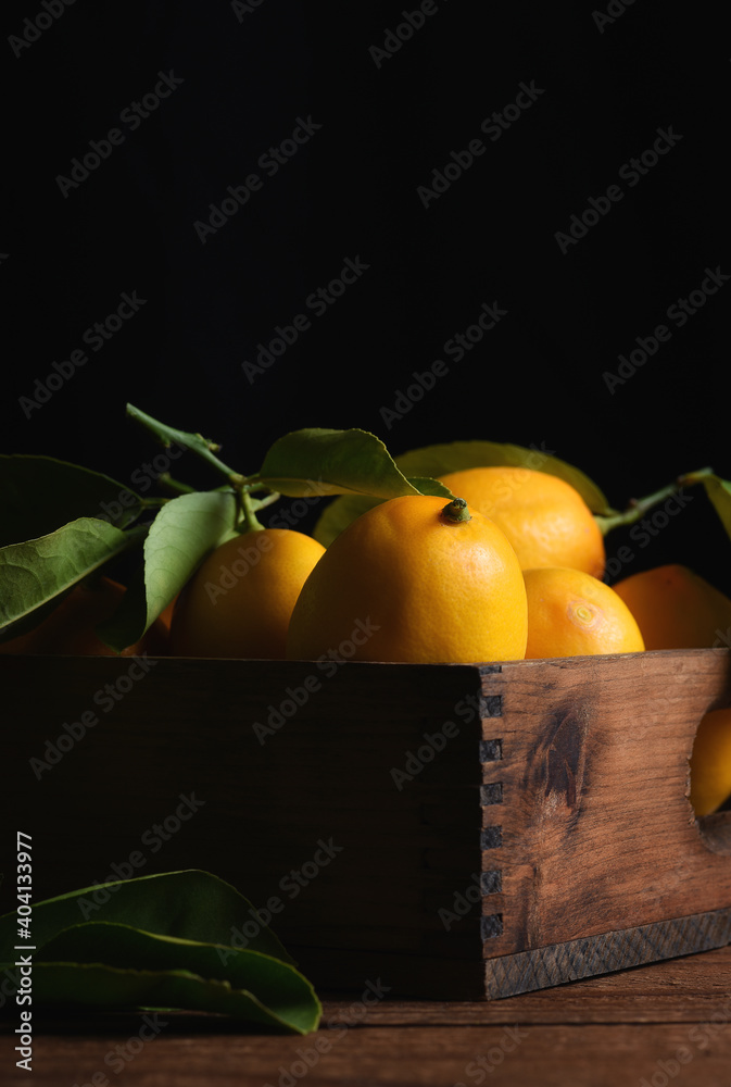 Fotografija Fresh Picked Lemons in a wood crate with black background.