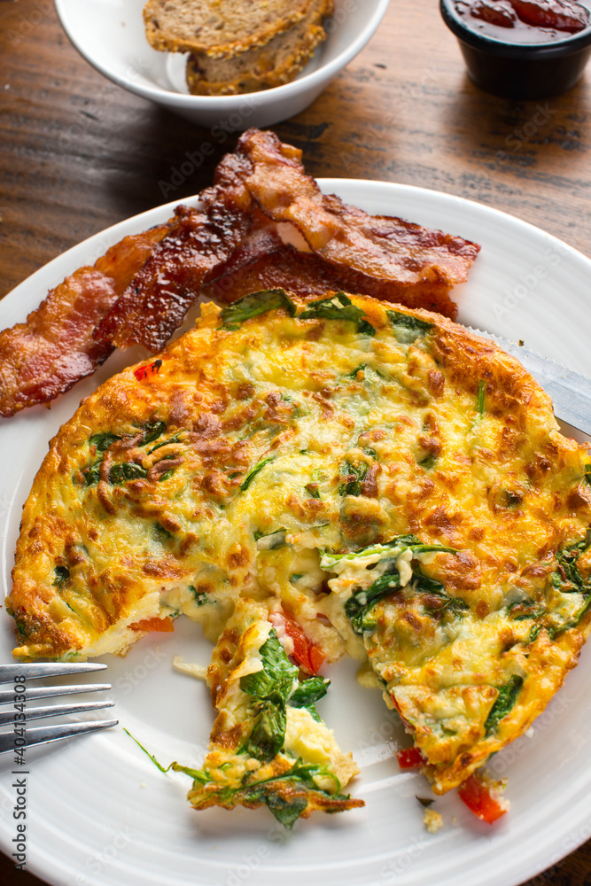 Omelette. Classic American brunch or breakfast menu item served at traditional American restaurant. Farm fresh eggs, cooked in butter with fresh vegetables pork, bacon, cheese and served with salad Omelette. Classic American brunch or breakfast menu item served at traditional American restaurant. Farm fresh eggs, cooked in butter with fresh vegetables pork, bacon, cheese and served with salad