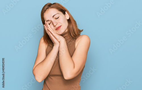 Young caucasian woman wearing casual clothes sleeping tired dreaming and posing with hands together while smiling with closed eyes.