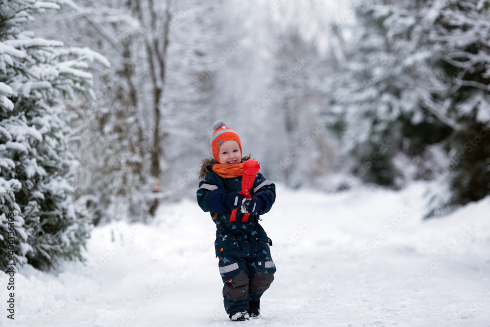 Pretty toddler girl wearing winter clothes having fun outside in snowy day