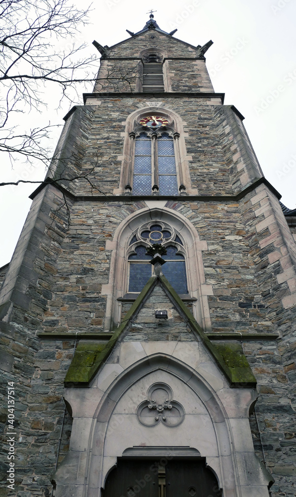 Fototapeta premium Kirche St. Peter und Paul in Kronberg im Taunus aus dem Mittelalter des 14. Jahrhunderts mit Steinfassade, Dekorationen und Dach aus Schiefer im Winter