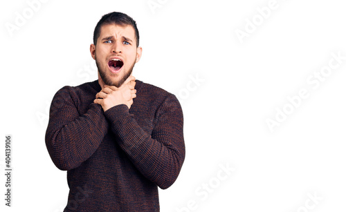 Young handsome man wearing casual sweater shouting and suffocate because painful strangle. health problem. asphyxiate and suicide concept.