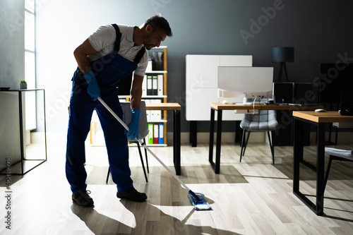 Male Janitor Mopping Floor In Face Mask © Andrey Popov