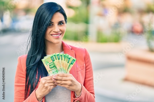 Young beautiful businesswoman smiling happy holding russian rubles banknotes at the city.