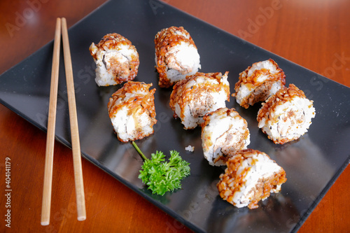 Salmon sushi typical of Japanese cuisine on black plate, natural light inside restaurant