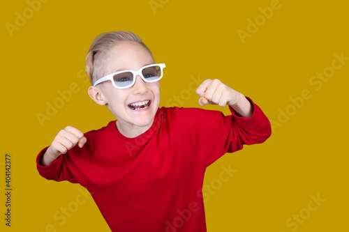 a child in children's 3D glasses joyfully raises his hands