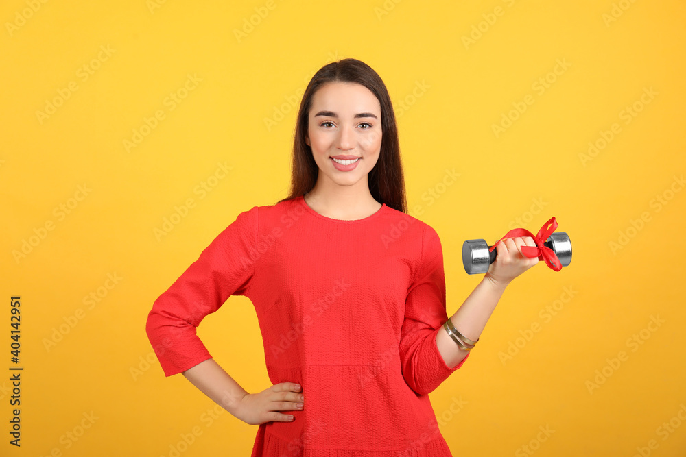 Woman with dumbbell as symbol of girl power on yellow background. 8 March concept Woman with dumbbell as symbol of girl power on yellow background. 8 March concept