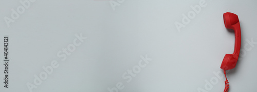 Hotline service. Red telephone receiver and space for text on light grey background, top view