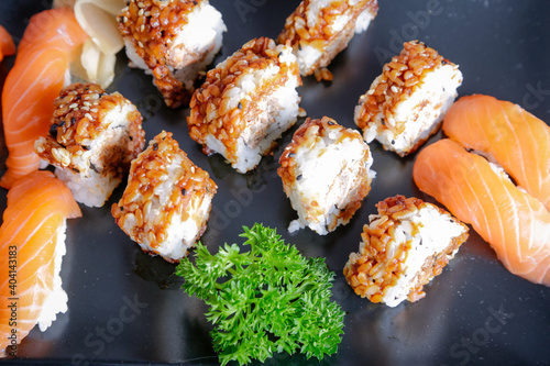 Salmon sushi typical of Japanese cuisine on black plate, natural light inside restaurant