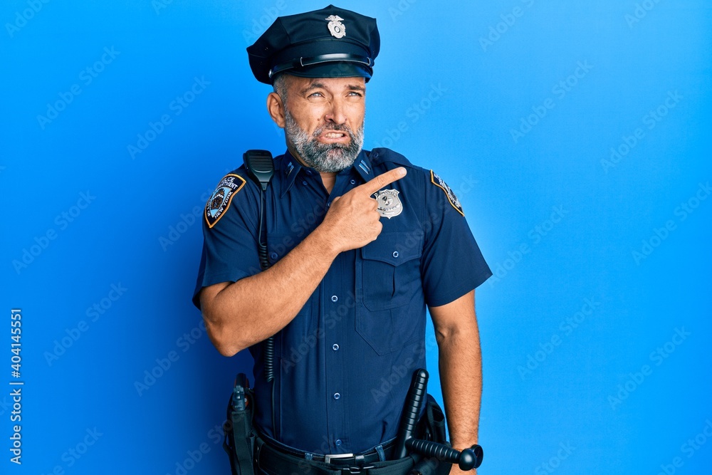 Middle age handsome man wearing police uniform pointing aside worried and nervous with forefinger, concerned and surprised expression