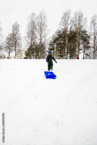 The child is sledding down the hill. Downhill skiing in winter.