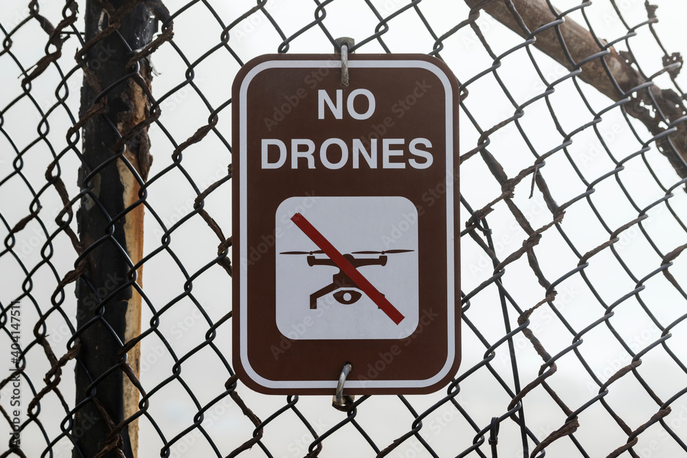 No drones warning sign on old rusty fence.  