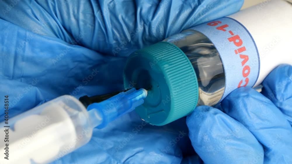 Hands of healthcare worker in protective gloves draw Covid-19 coronavirus vaccine into new disposable syringe from glass vial. Global epidemic. Close-up. Hands of healthcare worker in protective gloves draw Covid-19 coronavirus vaccine into new disposable syringe from glass vial. Global epidemic. Close-up.