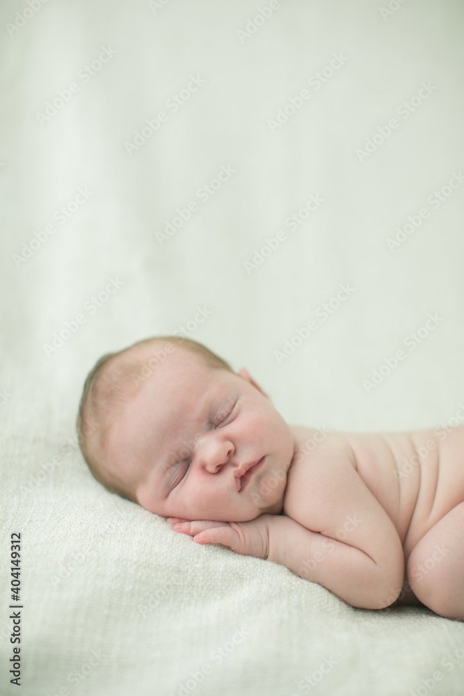 Close up of a sweet newborn infant baby girl laying on a cream-colored neutral blanket with copy space