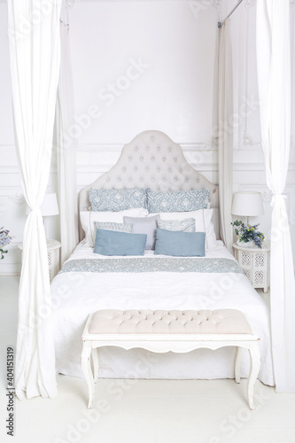 bright, clean stylish interior bedroom and living room with a large panoramic window. beautiful rich antique furniture. four-poster bed, a mirror and a sofa.