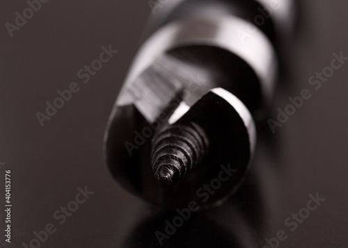 Drill on a dark background. Close-up of the tip of a metal drill.