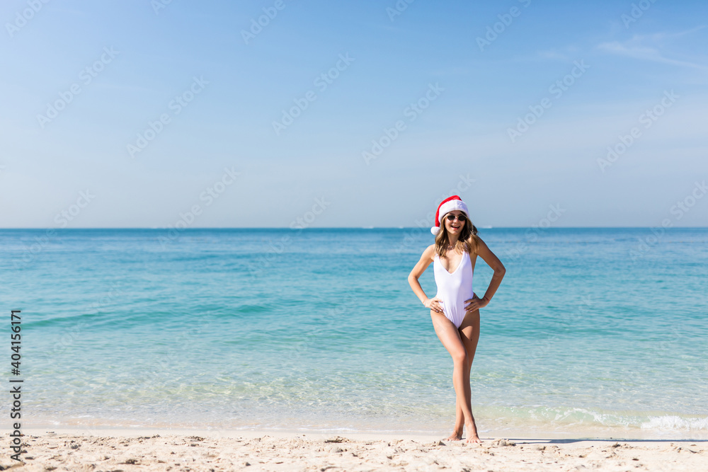 Young sexy woman in bikini and Santa hat enjoying freedom s at paradise beach