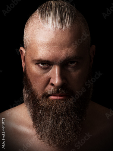Obraz na płótnie Handsome brutal caucasian bearded man in the dark. Studio portrait. Low key. Closeup. Vertical orientation. w salonie