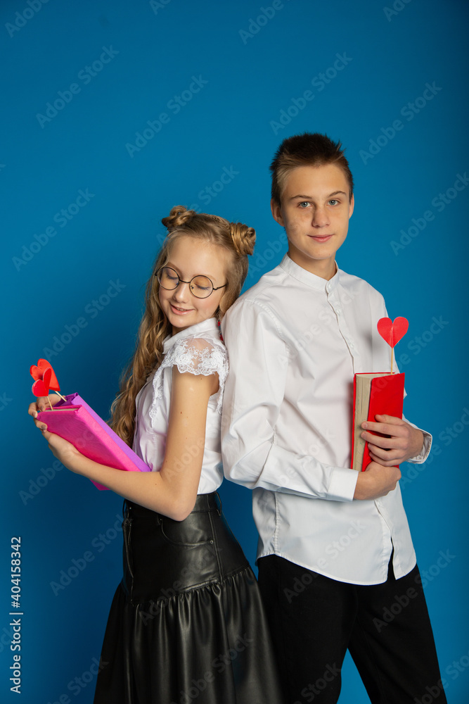 A couple of schoolchildren are teenagers on Valentine's Day on a blue background A couple of schoolchildren are teenagers on Valentine's Day on a blue background