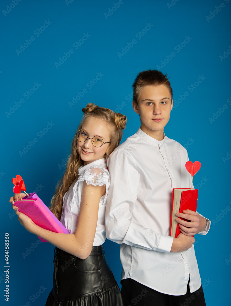 A couple of schoolchildren are teenagers on Valentine's Day on a blue background A couple of schoolchildren are teenagers on Valentine's Day on a blue background