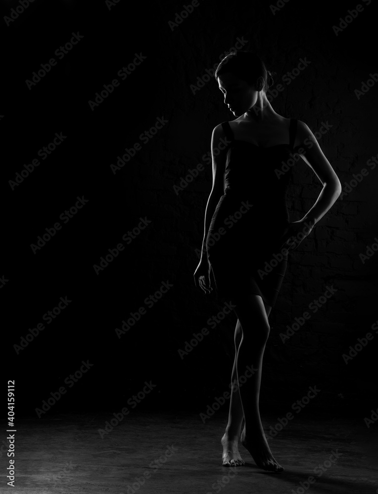 Dark silhouette of beautiful woman body on a dark background. Black and white photo.