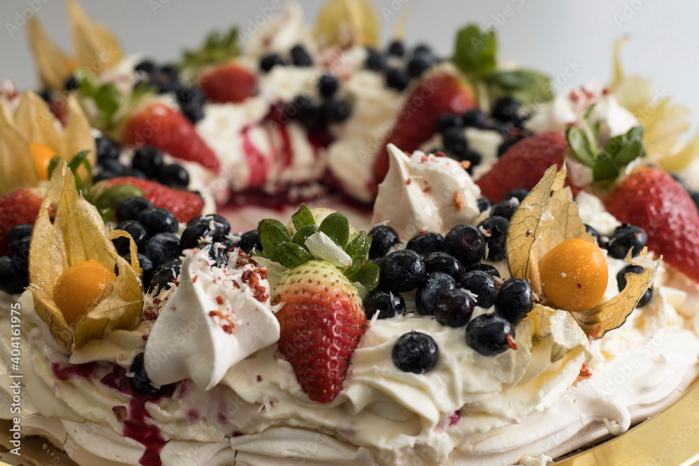 Delicious pavlova cake wreath of french meringue and whipped cream, decorated with strawberry, blueberries and physalis Delicious pavlova cake wreath of french meringue and whipped cream, decorated with strawberry, blueberries and physalis