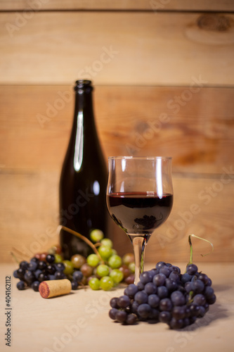 A glass of red wine with grapes and bottle