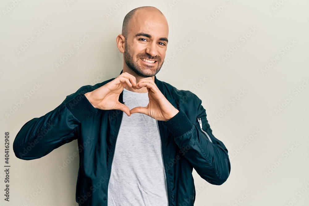 Young hispanic man wearing casual sporty jacket smiling in love doing heart symbol shape with hands. romantic concept. Young hispanic man wearing casual sporty jacket smiling in love doing heart symbol shape with hands. romantic concept.