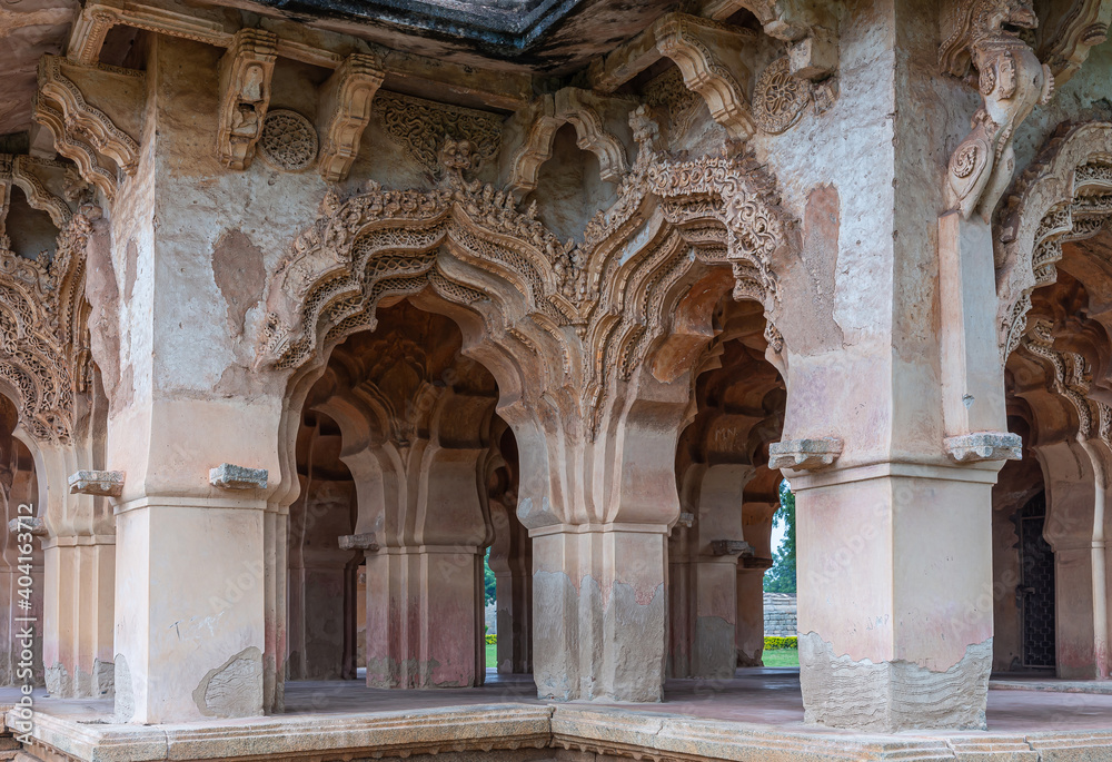 Hampi, Karnataka, India - November 5, 2013: Zanana Enclosure. Corner detail of brown and gray stone extensively decorated peacock arches over entrance gates. 