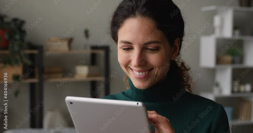 Pretty millennial woman holding tablet device looks at gadget screen smiles enjoy easy remote e-shopping, buy fashion clothes on internet webstore retail services. Happy modern technology user concept