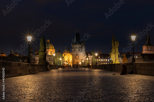 .old cobbled sidewalk with paving Charles Bridge in the center of Prague and in the background the old bridge tower at night in the Czech Republic and the light from street lighting