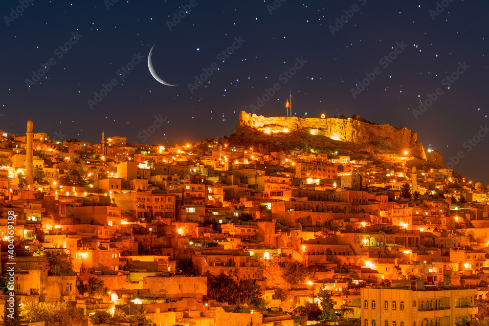 Ancient Mardin city at night under crescent and stars. Mardin night landscape.