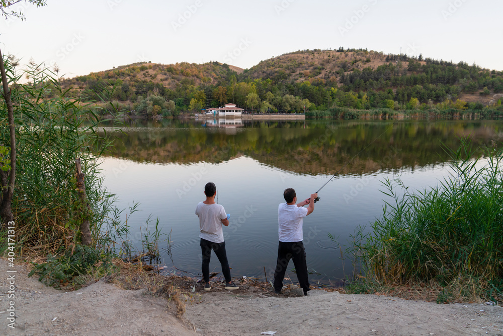 Fototapeta premium Back rear view of two fishermen in Eymir Lake, Ankara, Turkey