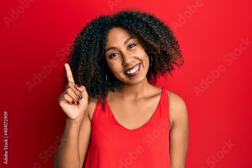 Beautiful african american woman with afro hair wearing casual clothes smiling with an idea or question pointing finger up with happy face, number one