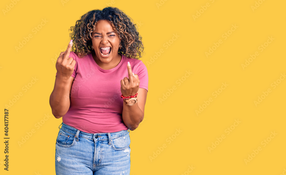Young african american plus size woman wearing casual clothes showing middle finger doing fuck you bad expression, provocation and rude attitude. screaming excited Young african american plus size woman wearing casual clothes showing middle finger doing fuck you bad expression, provocation and rude attitude. screaming excited